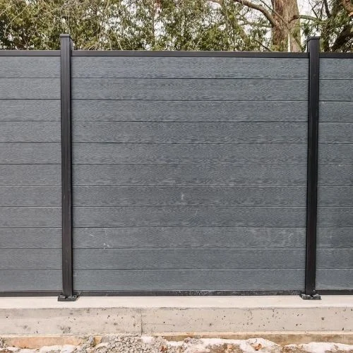 Gray privacy fence panels with black metal posts standing on a concrete base.